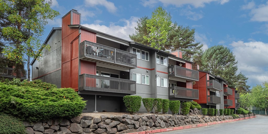 A red and grey apartment building with a stone wall in front.